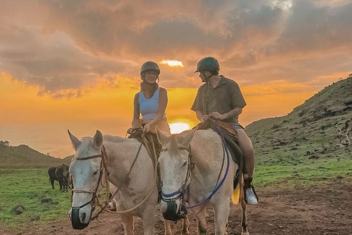 Two riders on horseback at sunset on the Pālehua trail above Kapolei, Oʻahu