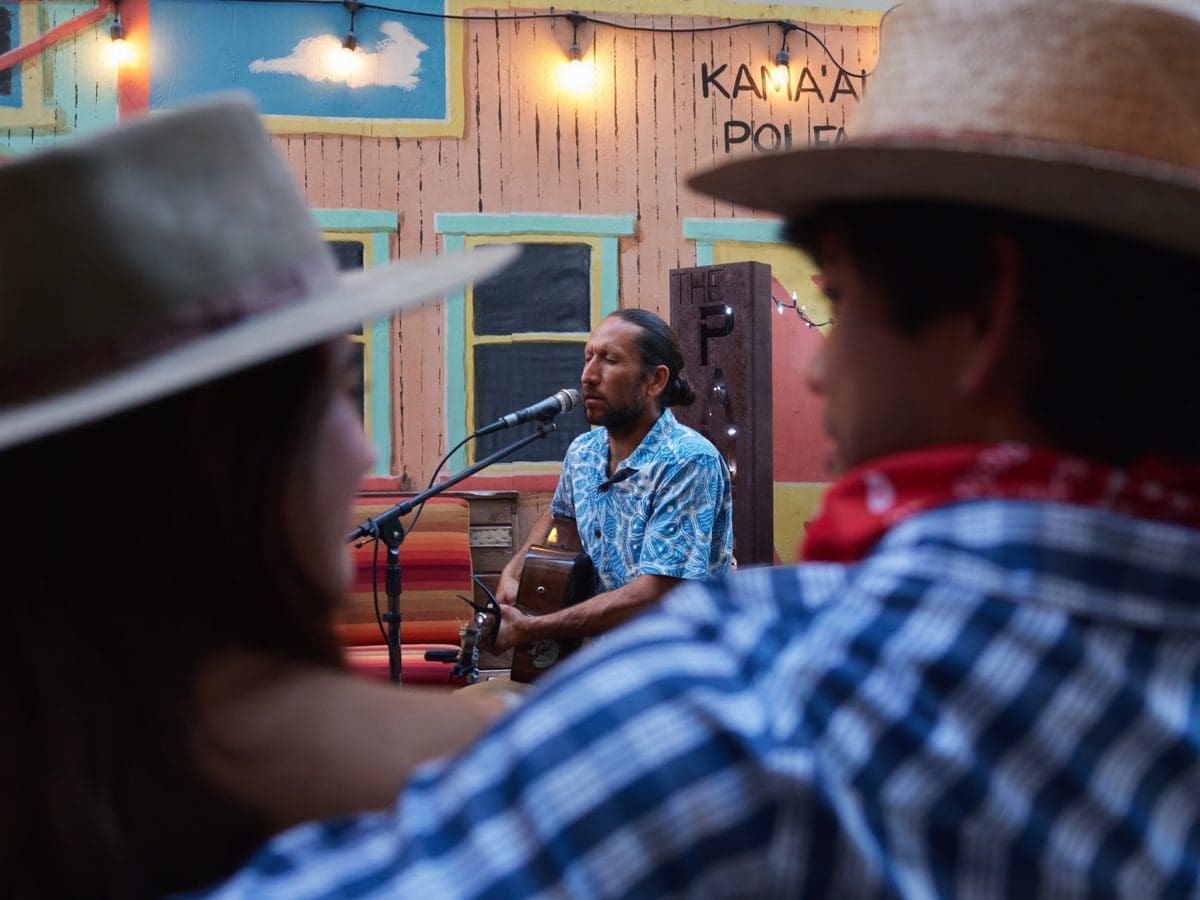 Guests in paniolo hats watch live slack-key music at the Paniolo Bar